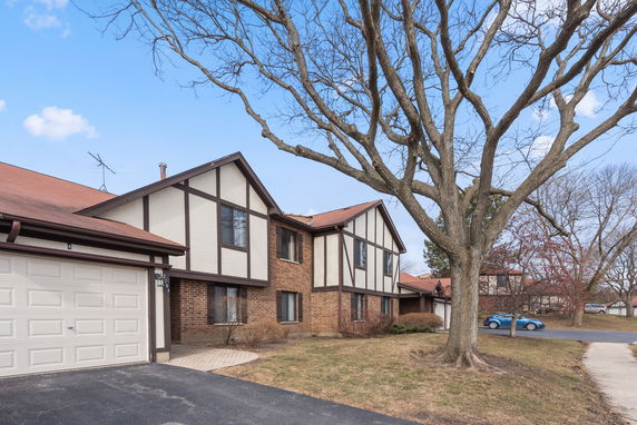 Front view of a two-story house with brick and Tudor-style elements.