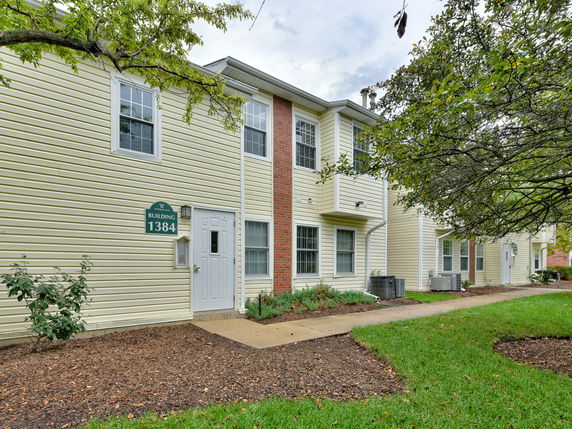 Front view of a two-story residential building with yellow siding and a white door.