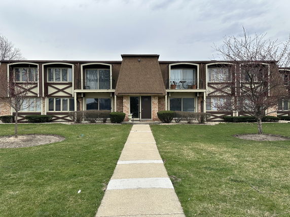 Front view of a two-story apartment building with a distinctive roof and balconies.