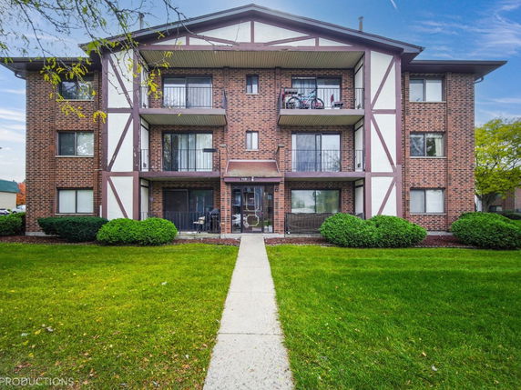 Front view of a multi-story brick apartment building with balconies.