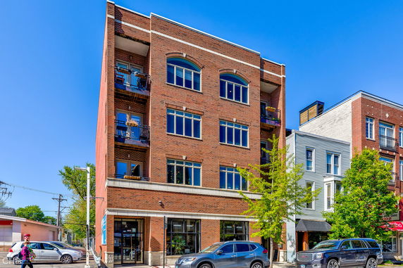 Front view of a multi-story brick building with large windows and balconies.
