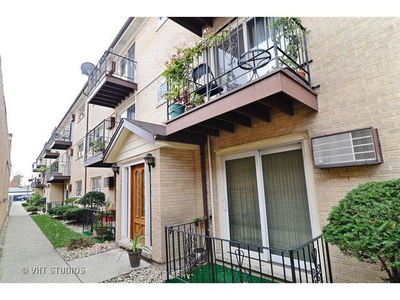 Three-story brick apartment building with balconies and a small front entryway.
