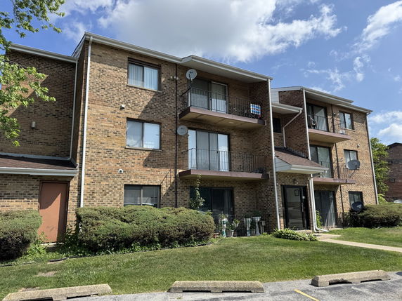 Front view of a multi-story brick residential building with balconies.