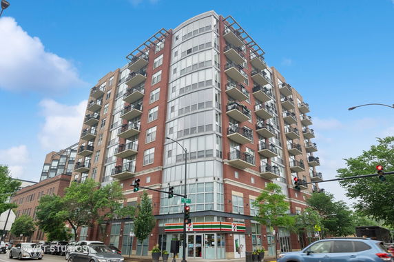 Front view of a multi-story apartment building with balconies and a retail store at the ground level.