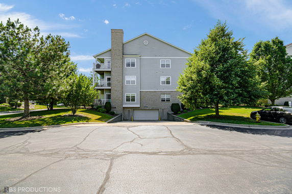 Front view of a multi-story residential building with balconies and a garage entrance.