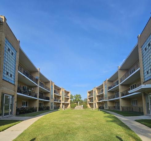 Front view of apartment buildings with balconies and brick facade.