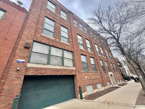 Front view of a multi-story brick building with several windows and a garage entrance.