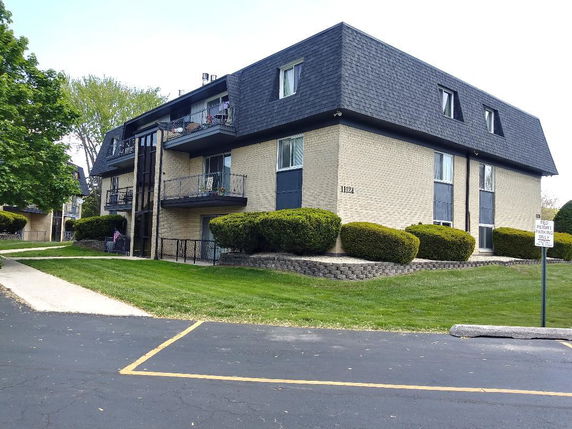 Front view of a three-story apartment building with a mansard roof.