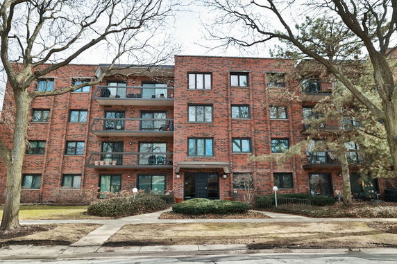 Front view of a multi-story brick apartment building with balconies.