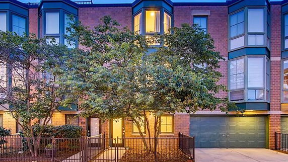 Front view of a three-story brick townhouse with a double garage.