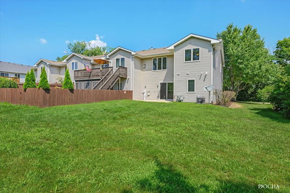 Rear view of a two-story house with a deck and staircase.