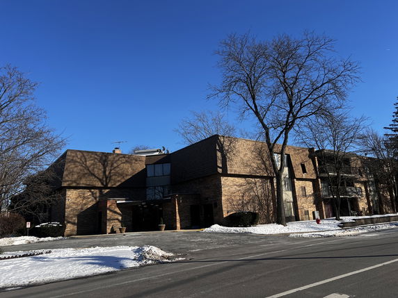 Front view of a multi-story brick building with a flat roof and balconies.