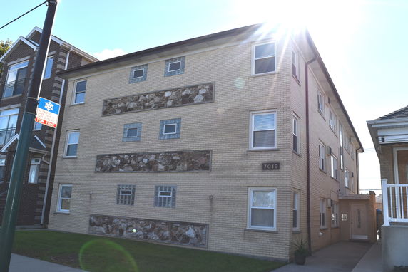 Front view of a three-story brick building with decorative stone elements.