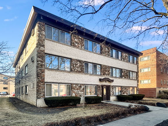 Front view of a three-story brick apartment building with multiple windows.