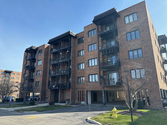 Front view of a multi-story brick apartment building with balconies.