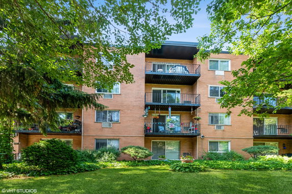Front view of a multi-story brick apartment building with balconies.