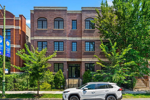Front view of a three-story brick building with black window frames.