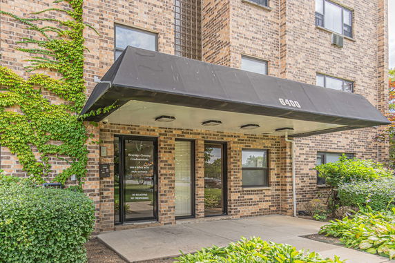 Front view of a brick condominium building with a black awning over the entrance.