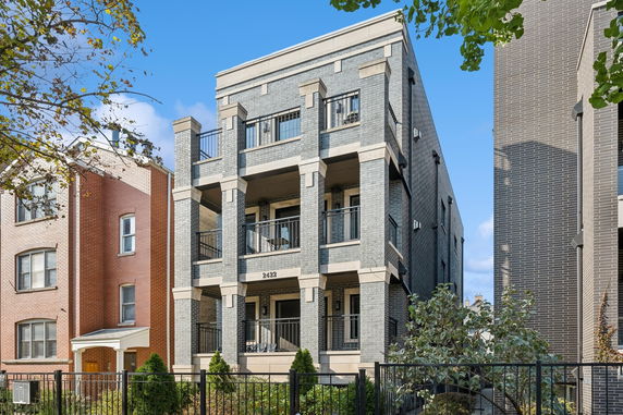 Front view of a multi-story brick apartment building with balconies.