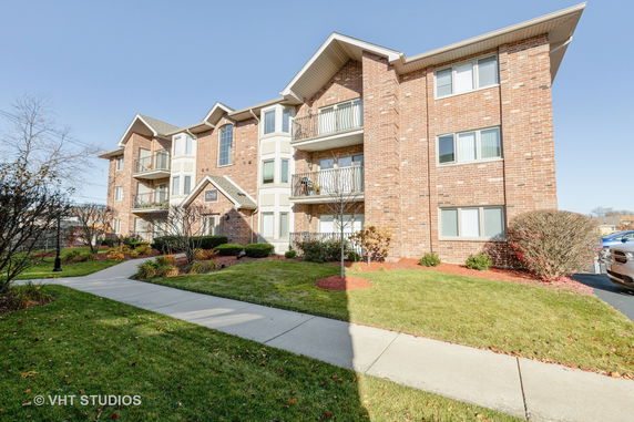 Front view of a three-story brick apartment building with balconies.