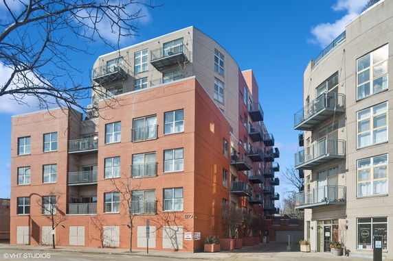 Front view of a multi-story brick and concrete apartment building with balconies.