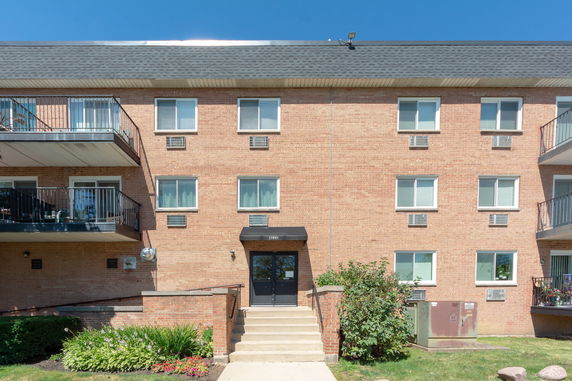Front view of a multi-story brick apartment building with balconies.