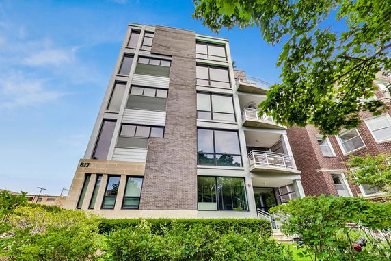 Front view of a multi-story modern apartment building with large windows and balconies.