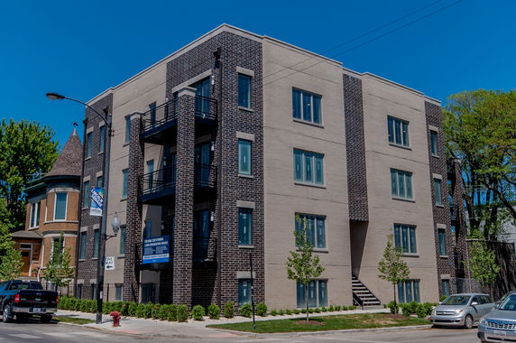 Front view of a multi-story apartment building with brick facade and large windows.
