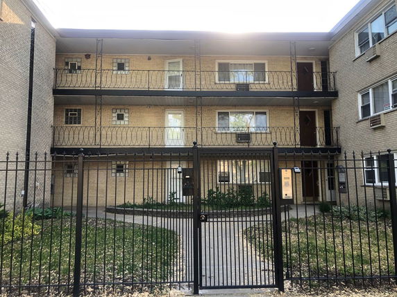 Front view of a three-story apartment building with a gated entrance.