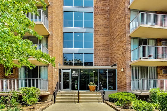 Front view of a multi-story brick building with balconies and a glass entrance.