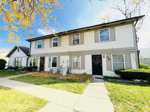 Front view of a two-story house with beige siding and dark trim.