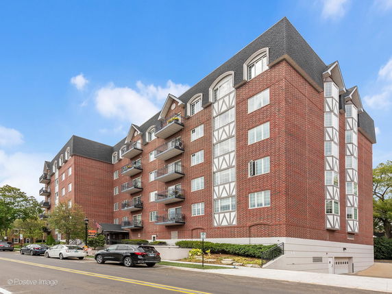 Front view of a multi-story brick apartment building with balconies.