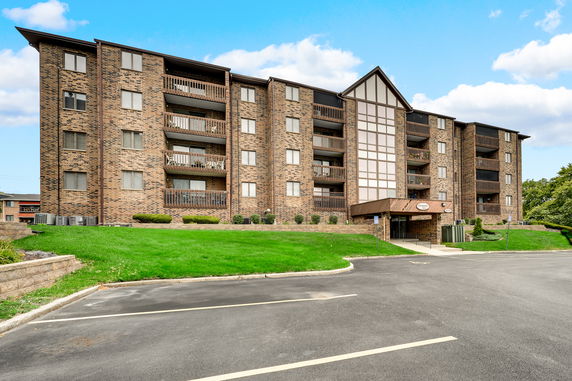 Front view of a multi-story brick apartment building with balconies.