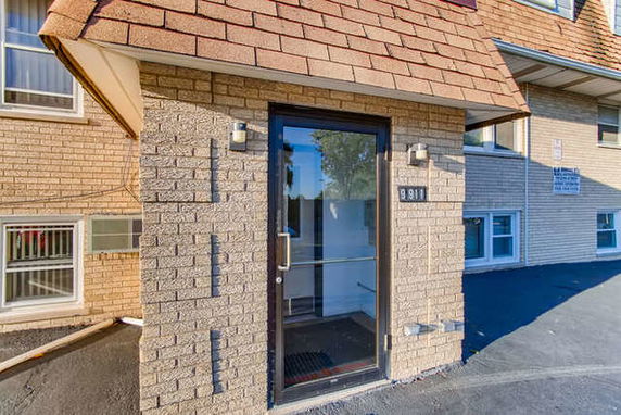 Front view of a building entrance with a glass door and brick exterior.