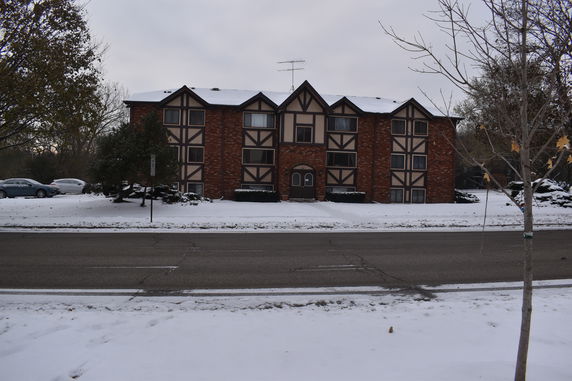 Front view of a three-story brick apartment building with snow-covered ground.