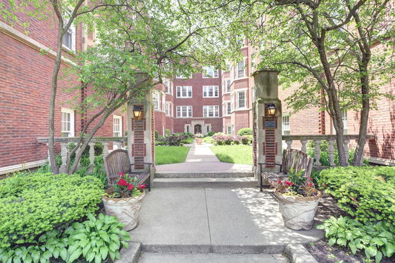 Front view of a multi-story brick building with decorative entryway and greenery.