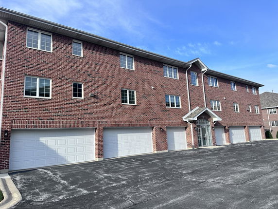 Front view of a three-story brick building with multiple garages.