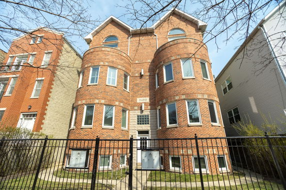 Front view of a multi-story brick building with rounded facade and multiple windows.