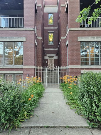 Front view of a brick multi-story building with a gated entrance.