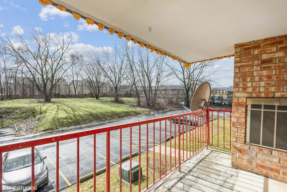 View from a balcony overlooking a parking area and grassy terrain with trees.