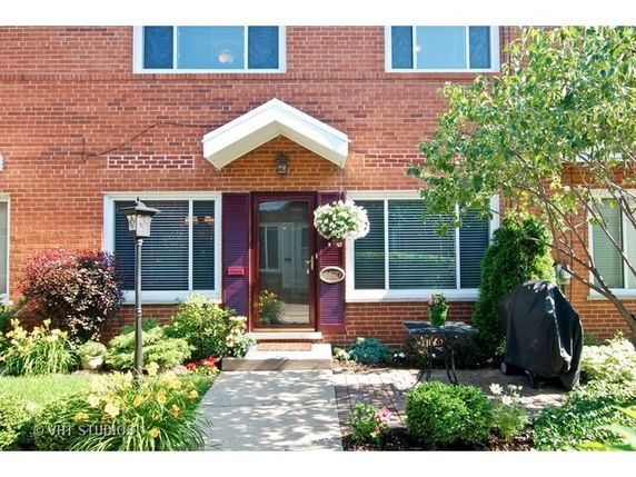 Front view of a brick house with a pathway leading to the entrance.