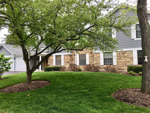 Front view of a house with a stone and gray siding exterior and a double garage.