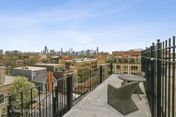 Panoramic view from a rooftop showing cityscape and distant skyline.