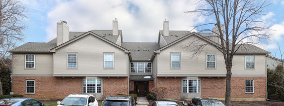 Front view of a two-story house with a brick and siding exterior and a central entrance.