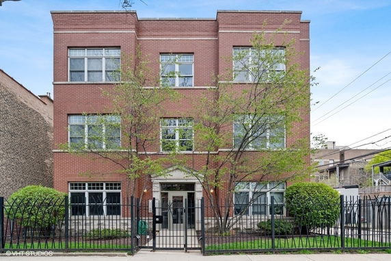 Front view of a three-story brick building with multiple windows.