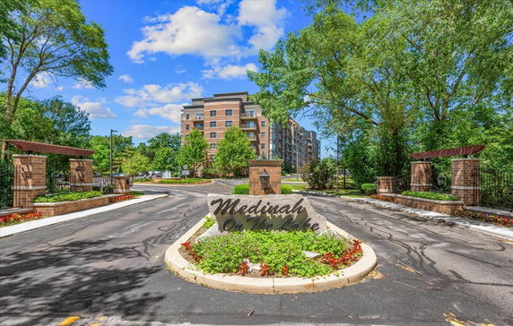 Front view of a multi-story residential building with a landscaped entrance.