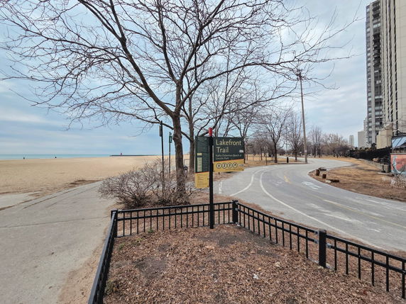 View of the Lakefront Trail with a sandy beach and nearby buildings.
