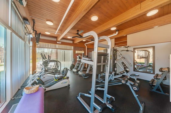 Gym area with exercise equipment and wooden ceiling.