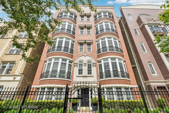 Front view of a multi-story brick building with multiple balconies and arched windows.