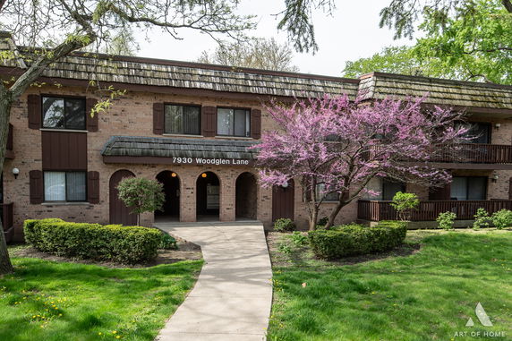 Front view of a two-story building with brown shutters and brick exterior.